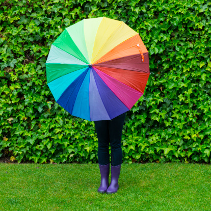 Young woman with playing with a colorful umbrella in a rainy day.