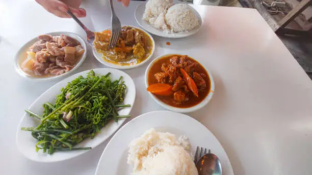 Overhead view of a tourist foodie eating at a carinderia or karinderya, common traditional eatery in the Philippines that serves affordable authentic local food