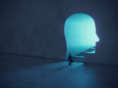 Business man standing in front of glowing portal gate shaped of human head. (3d render)