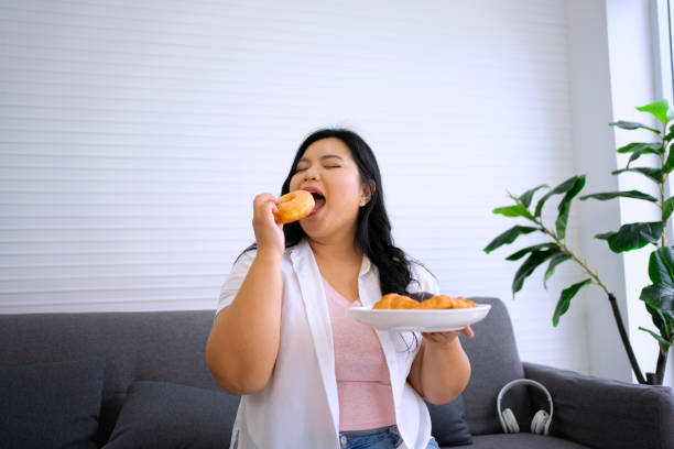 istock Plus size woman is eating donut. 1686495860