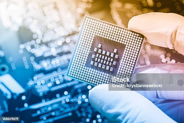 Technician Holding Chip Over Defocused Circuit Board Stock Photo - Download Image Now