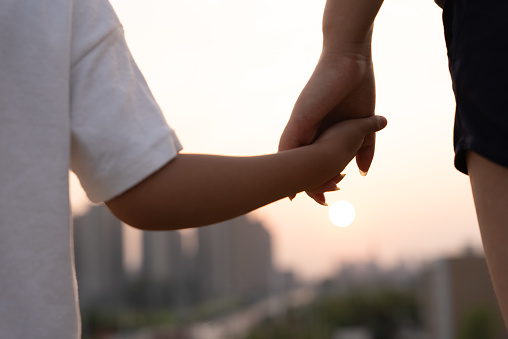 Close up of mother holding a child hands at the sunset