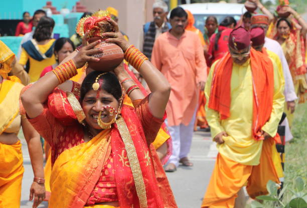 während der bhagwat katha-zeremonie gehen frauen in traditioneller kleidung mit einer kalash auf dem kopf zum tempel. - international society for krishna consciousness stock-fotos und bilder