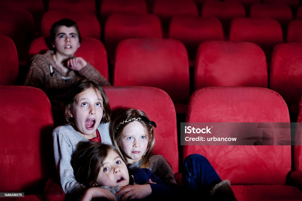 Watching a scary movie Four children watching a scary movie, three young children huddling together with fearful expresions Horror Movie Stock Photo