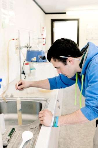 A winery employee using equipment to test the specific gravity of the wine.  One of the steps involved in the production of wine in a Devon winery