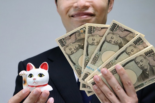 A photo depicting people getting rich with the blessings of a beckoning cat