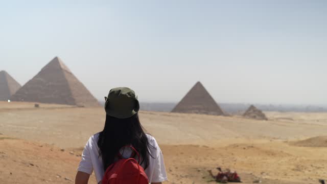 asian traveler Woman walking on desert on the background of Giza pyramids