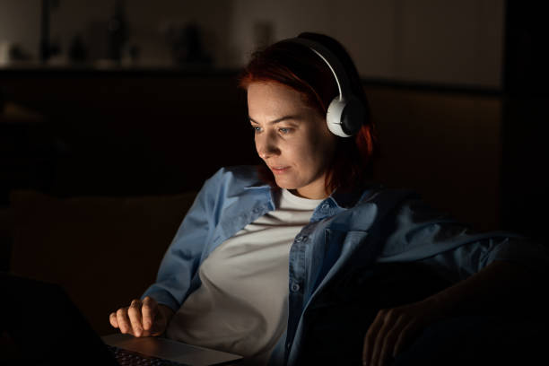 istock Concentrated middle aged programmer female sits on chair work on laptop at night. Freelancr concept 1686605321