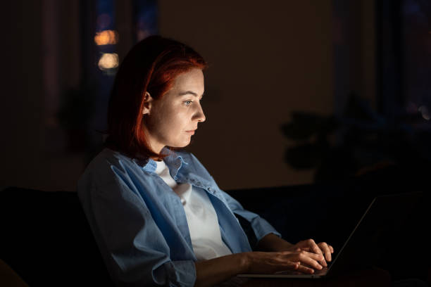 istock Concentrated middle aged programmer female sits on chair work on laptop at night. Freelancr concept 1686605328