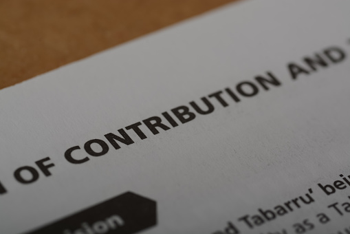 Close up view of the word CONTRIBUTION. contribution typically refers to the financial support or investment that an individual, organization, or entity provides to a cause, project, business, or endeavor.