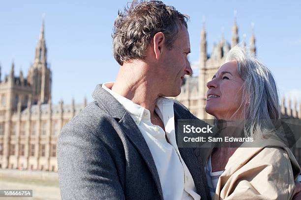 Foto de Casal Feliz Abraçando Na Frente Dos Edifícios Do Parlamento Em Londres e mais fotos de stock de 55-59 anos