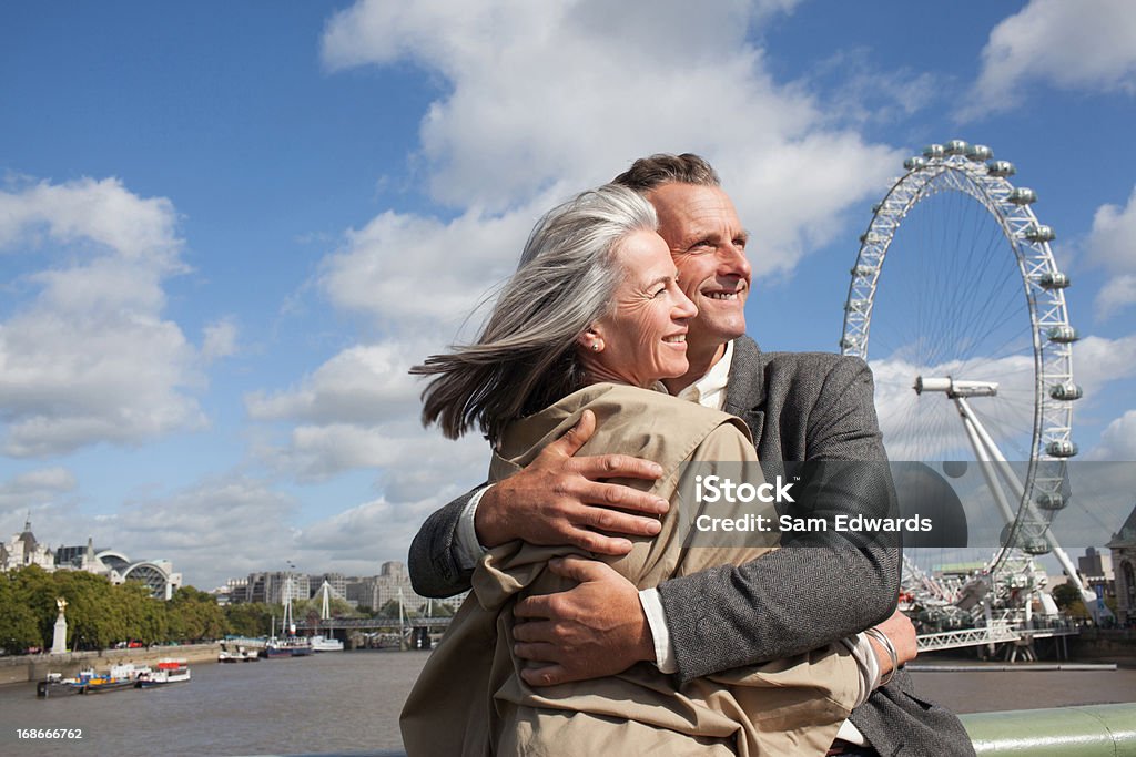 Retrato de sorrindo casal abraçando na frente do rio Tâmisa - Foto de stock de Casal de Meia Idade royalty-free
