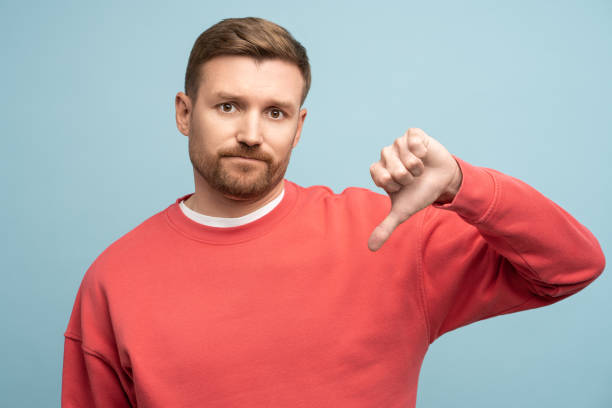 istock Displeased irritated man showing thumb down dislike gesture isolated on studio blue background. 1686676858
