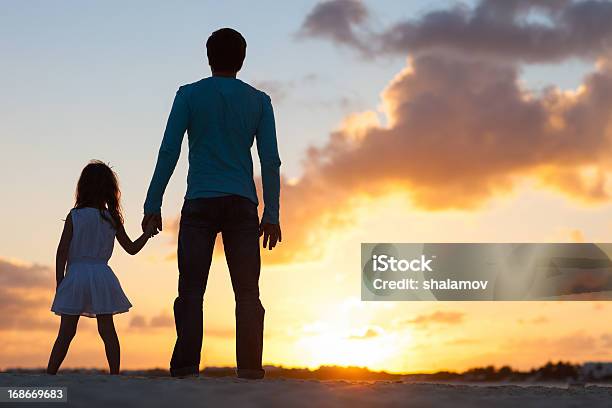 Father And Daughter Holding Hands Watching Sunset Stock Photo - Download Image Now - Adult, Back Lit, Beach