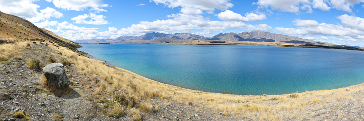 Lake Tekapo panorama taken from part of the Mt John Summit Circuit Track. The photo looks east across the water to the Two Thumb mountain range of the Southern Alps of New Zealand.