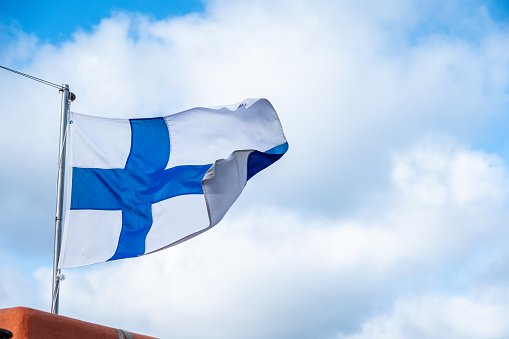 Flag of Finland with blue sky and clouds