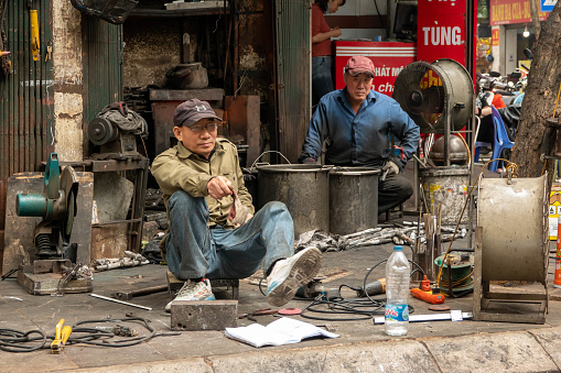A metal workshop on the street in Hanoi, Vietnam. Two men take a break