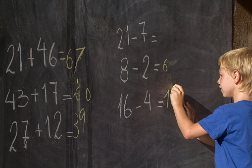 boy studying mathematics on black board