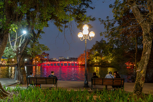 A beautiful night cityscape of a public park with landscaped canal and a walking bridge.