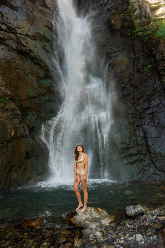 Cheerful woman swimming in waterfall