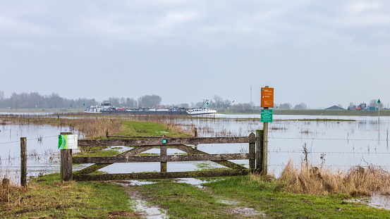 Olst Wijhe, The Netherlands - January 21, 2023: Flooded entrance to walking area near ferry pond Olsterveer at crossing IJssel river in Olst Wijhe Welsum in Overijssel in The Netherlands