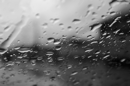 Blurred background of rain drops falling on the car windshield on a rainy day.