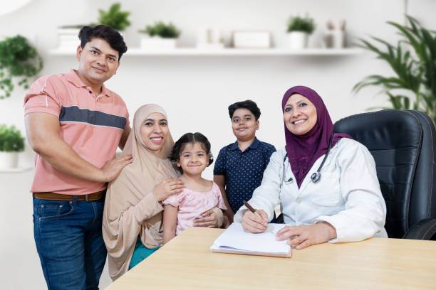 portrait d’une femme musulmane médecin consultant de jeunes patients avec deux enfants dans une clinique moderne. famille avec pédiatre généraliste souriant regardant la caméra. - men pakistani ethnicity islam malaysian person photos et images de collection