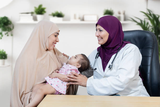 happy young muslim mother wearing with her cute little baby visiting general pediatrician in modern clinic for routine check-up, healthcare and medical concept. women wearing headscarf. - healthcare and medicine nurse doctor general practitioner imagens e fotografias de stock