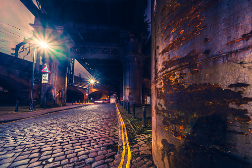 Dark and gloomy industrial atmosphere under the historical rail bridges in Manchester