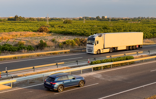 Semi truck with Semi-trailer driving along highway. Goods Delivery by roads. Services and Transport logistics. Highway with transport, car and truck, road landscape. Road traffic on motorway.