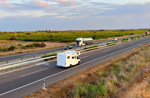 Campervan drive on highway. Family camper van driving on motorway. Motorhome lifestyle travel to sea and mountains. Travel along Spain coast. Traffic cars on road.