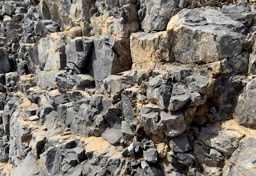 Granite Stone background, rock texture. Wall stone Granite background. Rock with cracks and layers. Rough rocky texture of mountains. Mining and geology. Texture of marble wall.