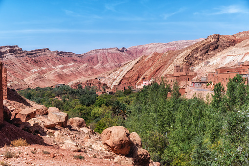 Overview of a typical Berber village in Dades gorge along the former route of the caravans, Atlas Mountains, Morocco. Pink and red houses, red mountains and green trees. Oasis in the desert.