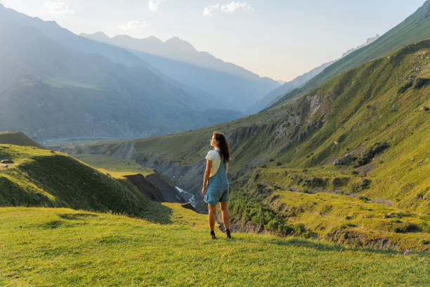 Woman standing on the background of mountains at sunset Carefree woman enjoying nature and standing on the background of mountains at sunset caucasus stock pictures, royalty-free photos & images