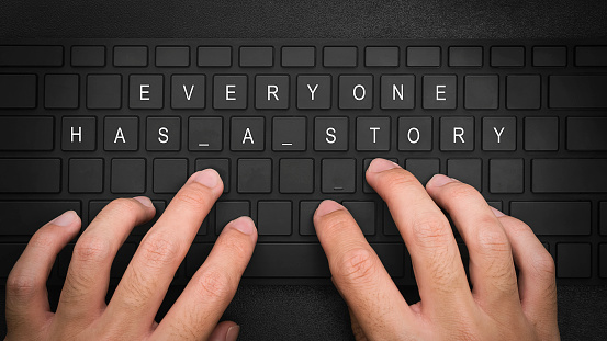 everyone has a story. Hand typing on desktop office computer keyboard. Writer typing on a computer or laptop keyboard.