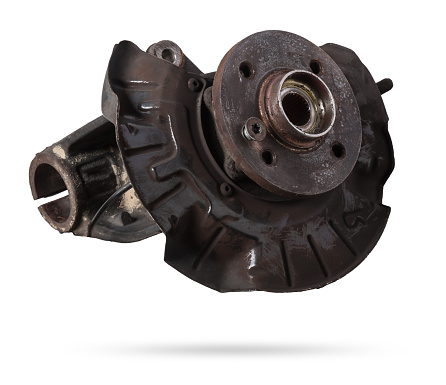 A close-up of a worn metal wheel hub with oil and rust elements on a white background. Seasonal undercarriage repair and replacement of brake system parts in a workshop.