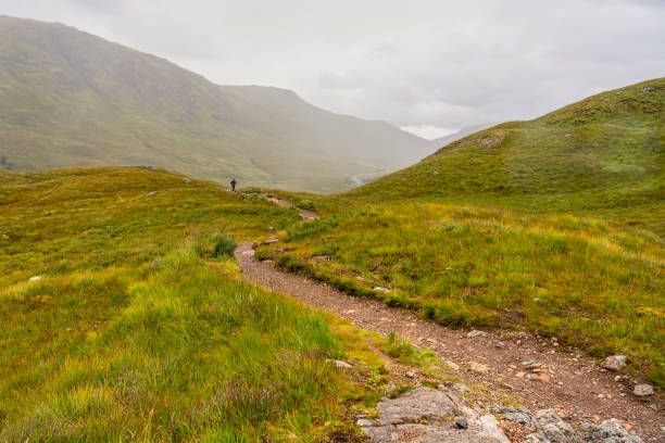 istock Hiker walking the path between mountains and green meadows in Glencoe, Scotland. 1686853740