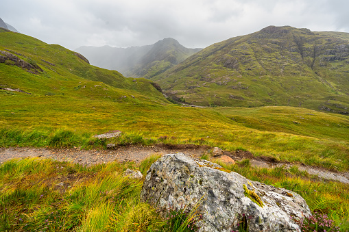 Fog-covered green mountains and hiking trails in the Glencoe Valley, Scotland