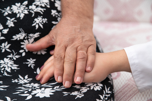 Aasian grandmother and grandchild holding hands on white background