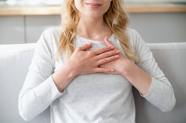 ruhige frau, die händchen auf herzbrust hält und dankbar ist - spirituality hand on heart meditating women stock-fotos und bilder