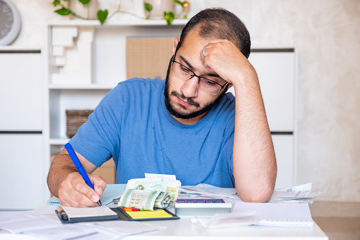 young bearded male callculating living costs in living room