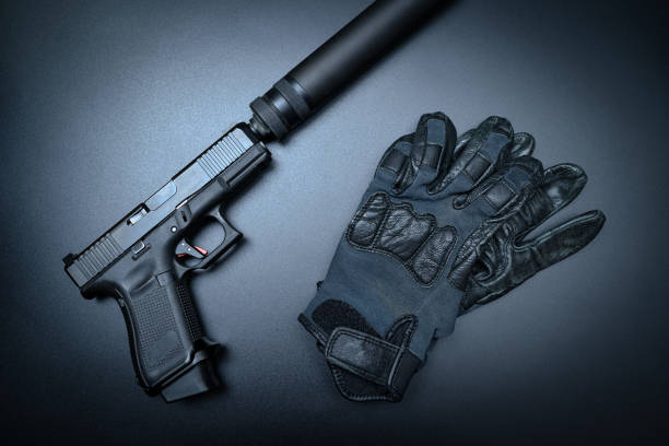 istock Pistol with silencer and gloves on the black background 1686914690