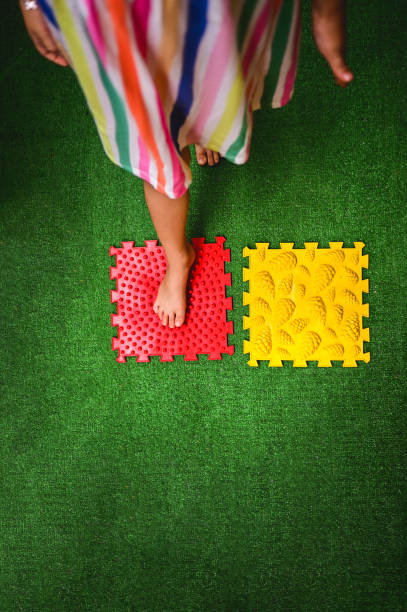 masseur de pieds. enfant sur tapis de massage faisant des exercices. - yellow color image textured sensory perception photos et images de collection