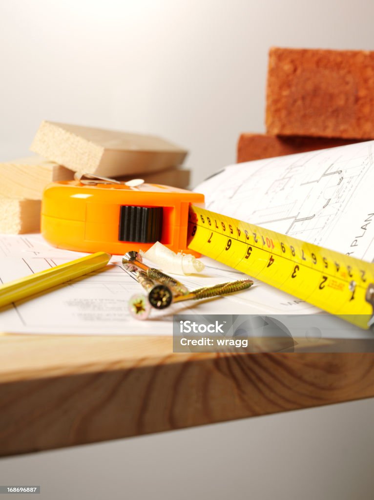 Construction on a Timber Work Bench House blueprints with tape measure, screws and building bricks. Copy space Bench Stock Photo