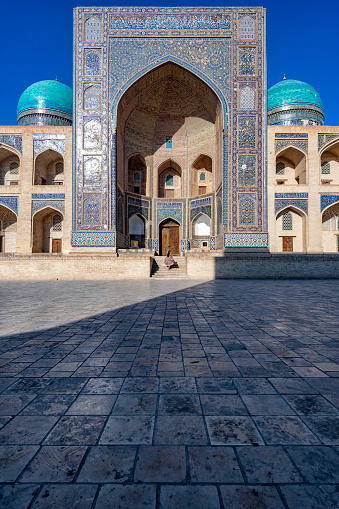 From far away, a lady is climbing the stairs of the blue mosque in Bukhara, Uzbekistan