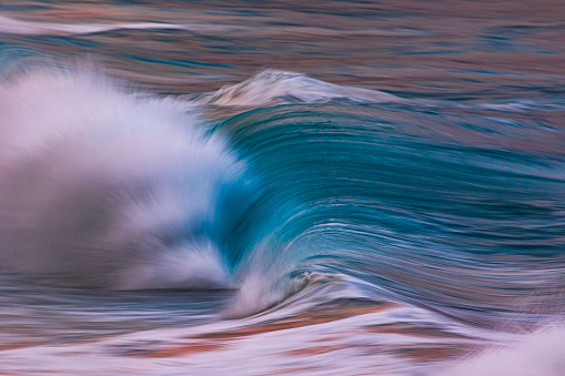 Smooth artistically captured blue ocean wave breaking in golden evening light. Photographed along the coastline of South Western Australia.