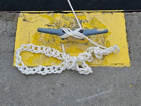 Chain sinnet knot using a white rope secured to a metal dock cleat