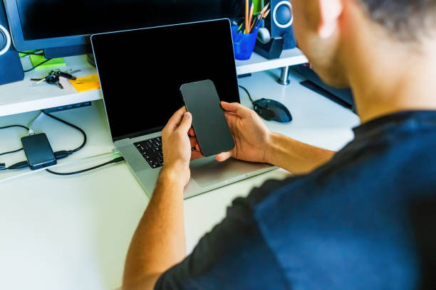 20 years old man working from home using smartphone and laptop.