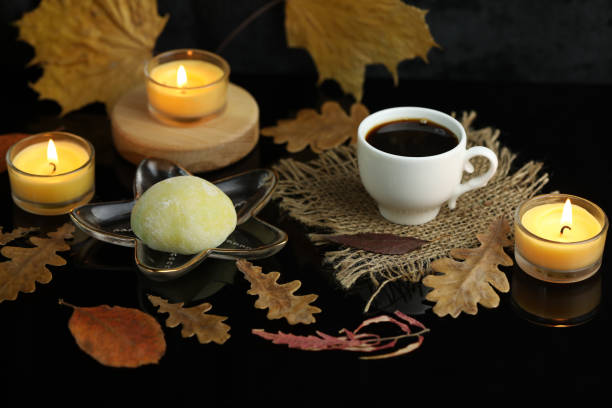 Daifuku color sweets with cup of coffee, candles and autumn leaves