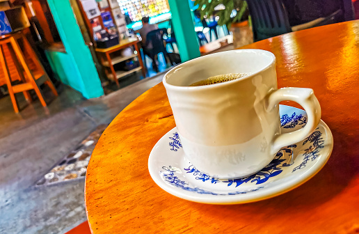 Blue and white cup pot with black coffee americano on wooden table in El Cafecito in Zicatela Puerto Escondido Mexico.